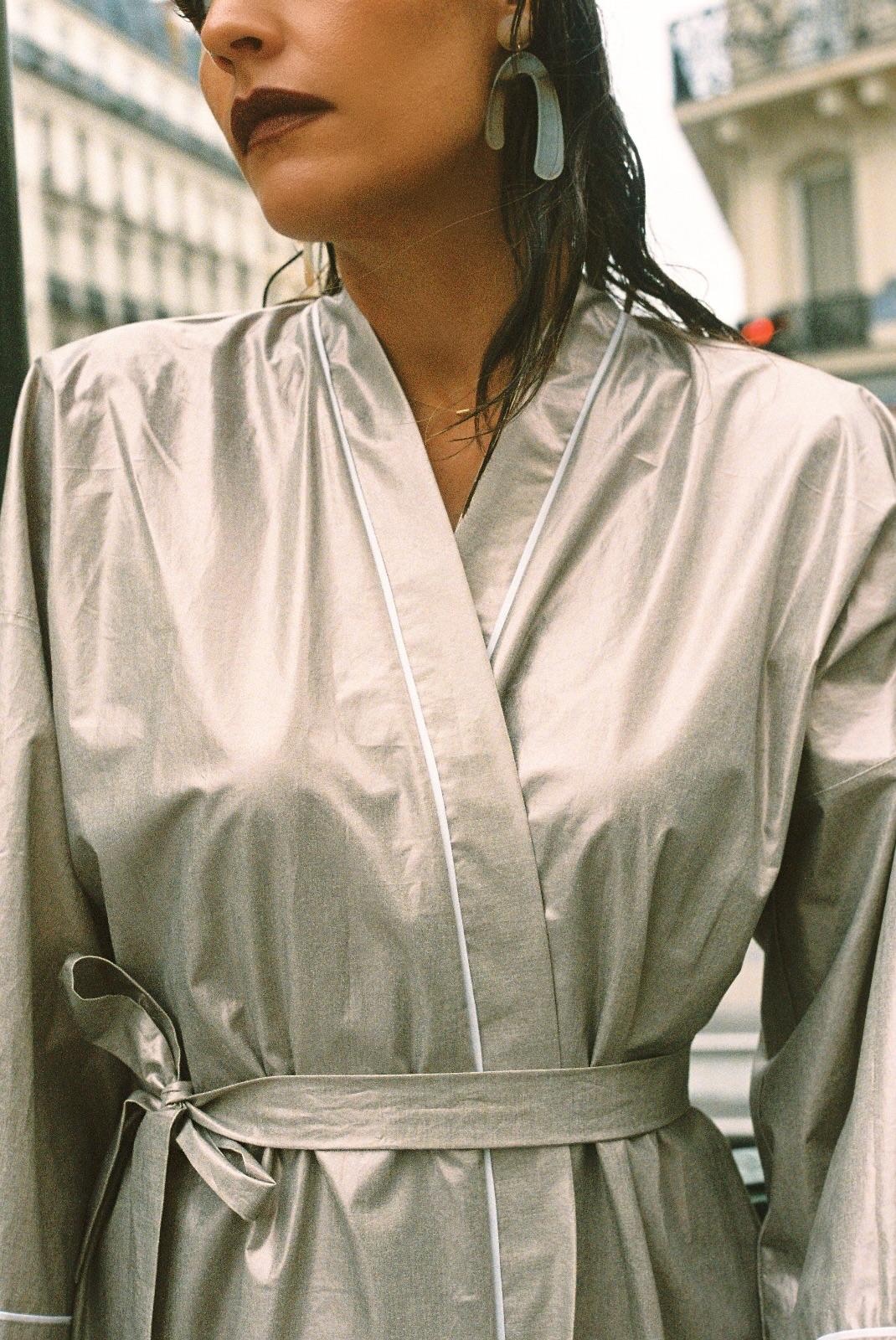 Atelier Sarita – Kimono Crystal en popeline de coton argenté. Long kimono fluide à la coupe affirmée, ceinturé à la taille, confectionné à la main à Paris en série limitée. Une pièce audacieuse et urbaine, inspirée des reflets minéraux et des lumières de l’architecture parisienne.