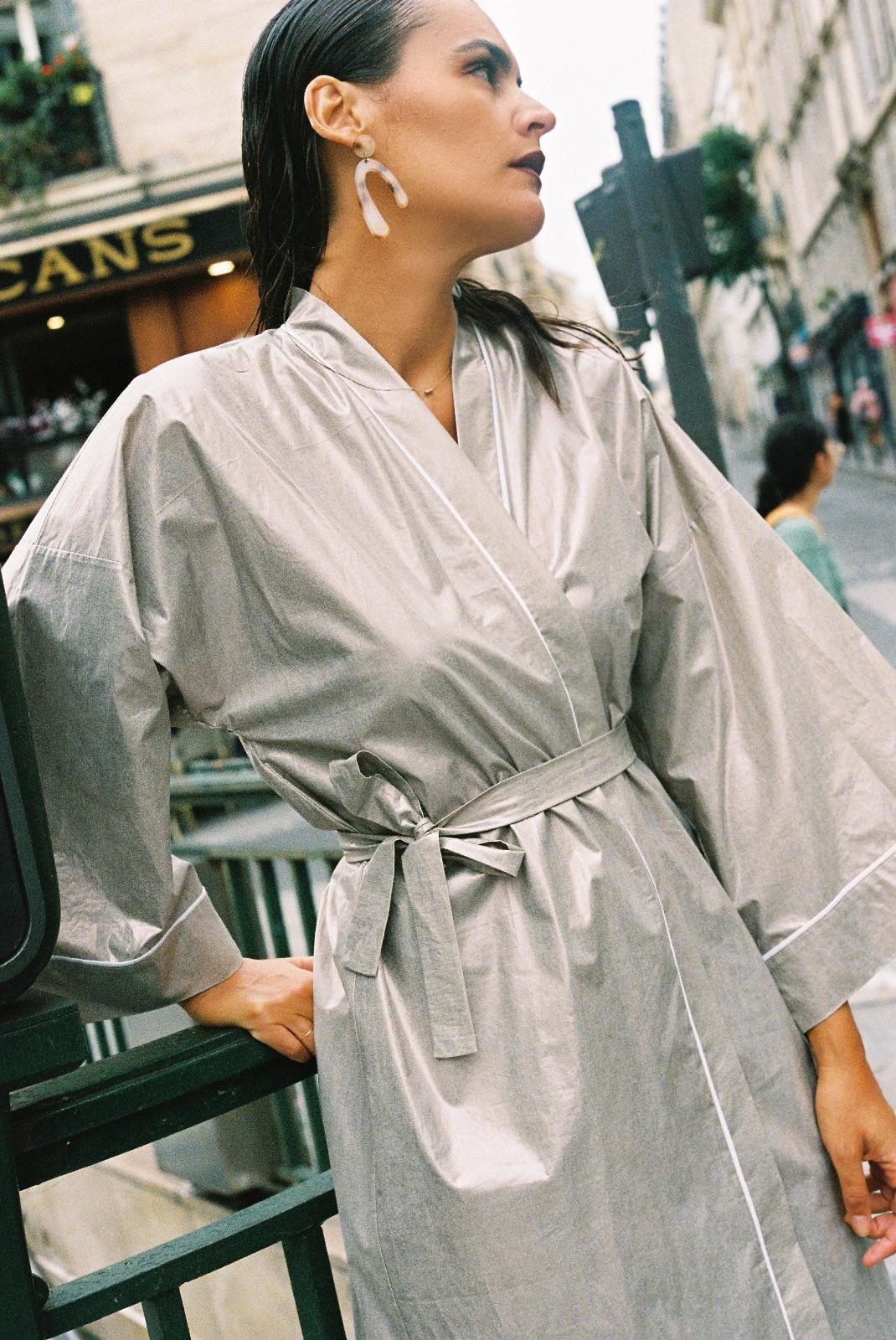 Atelier Sarita – Kimono Crystal en popeline de coton argenté. Long kimono fluide à la coupe affirmée, ceinturé à la taille, confectionné à la main à Paris en série limitée. Une pièce audacieuse et urbaine, inspirée des reflets minéraux et des lumières de l’architecture parisienne.