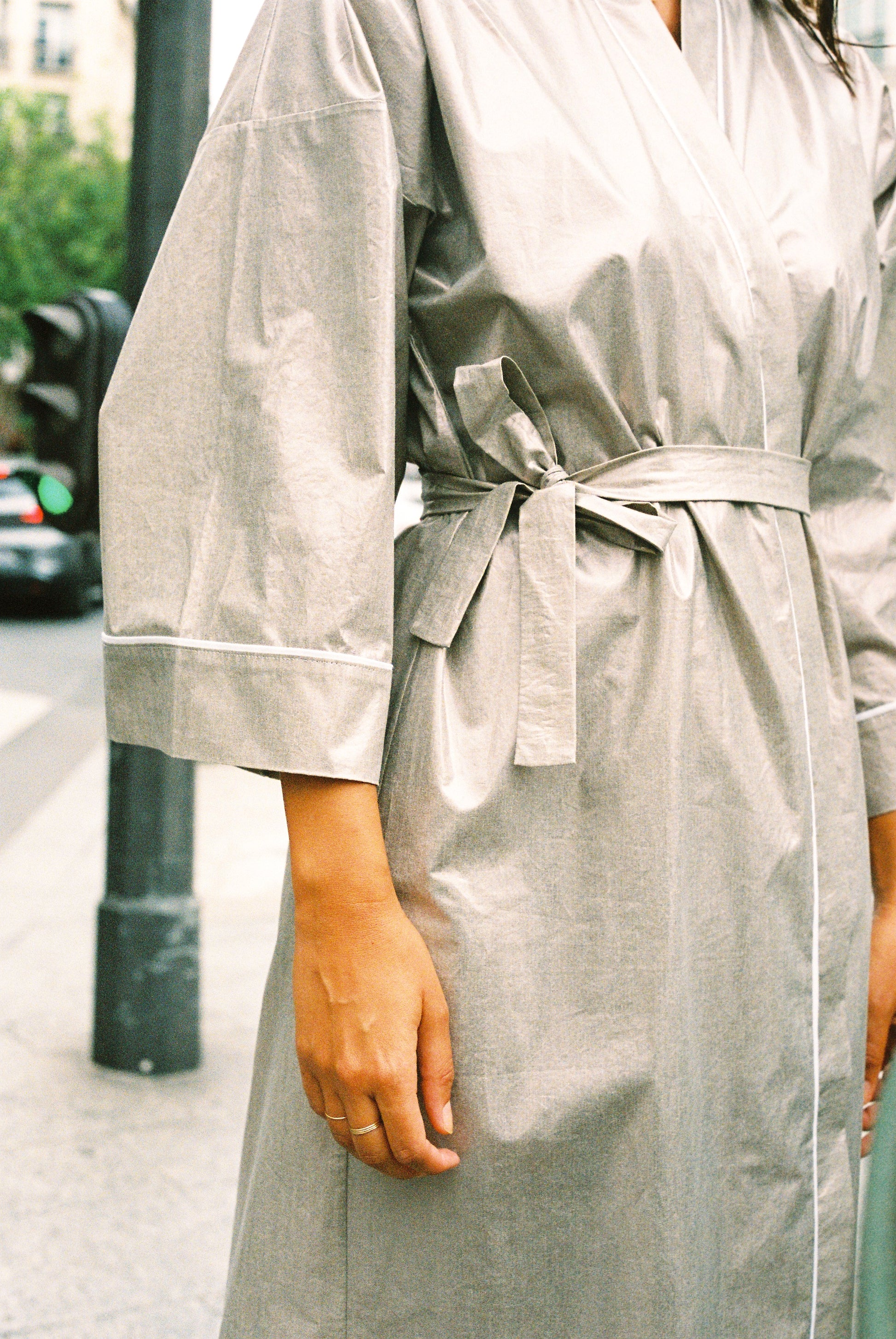 Atelier Sarita – Kimono Crystal en popeline de coton argenté. Long kimono fluide à la coupe affirmée, ceinturé à la taille, confectionné à la main à Paris en série limitée. Une pièce audacieuse et urbaine, inspirée des reflets minéraux et des lumières de l’architecture parisienne.