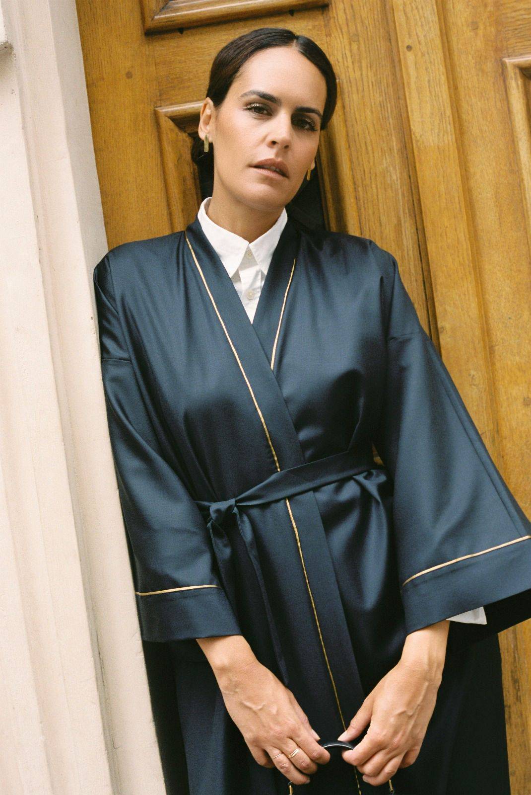 Atelier Sarita – Kimono Garnier en laine de costume bleu marine, rehaussé de délicats passepoils en soie dorée. Une coupe longue et fluide, inspirée de l’élégance intemporelle de l’Opéra Garnier, qui incarne la grandeur et la finesse de l’architecture parisienne. Fabriqué à la main à Paris en série très limitée, ce kimono allie la profondeur classique du bleu marine à la lumière subtile de l’or, pour une silhouette sophistiquée et affirmée.