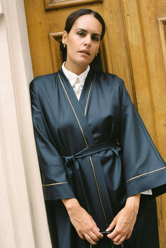 Atelier Sarita – Kimono Garnier en laine de costume bleu marine, rehaussé de délicats passepoils en soie dorée. Une coupe longue et fluide, inspirée de l’élégance intemporelle de l’Opéra Garnier, qui incarne la grandeur et la finesse de l’architecture parisienne. Fabriqué à la main à Paris en série très limitée, ce kimono allie la profondeur classique du bleu marine à la lumière subtile de l’or, pour une silhouette sophistiquée et affirmée.