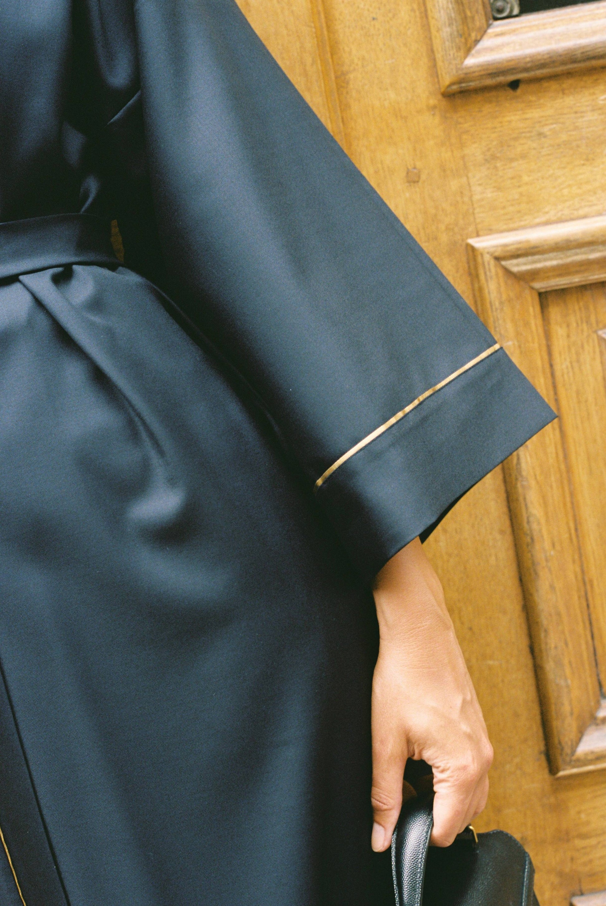 Atelier Sarita – Kimono Garnier en laine de costume bleu marine, rehaussé de délicats passepoils en soie dorée. Une coupe longue et fluide, inspirée de l’élégance intemporelle de l’Opéra Garnier, qui incarne la grandeur et la finesse de l’architecture parisienne. Fabriqué à la main à Paris en série très limitée, ce kimono allie la profondeur classique du bleu marine à la lumière subtile de l’or, pour une silhouette sophistiquée et affirmée.