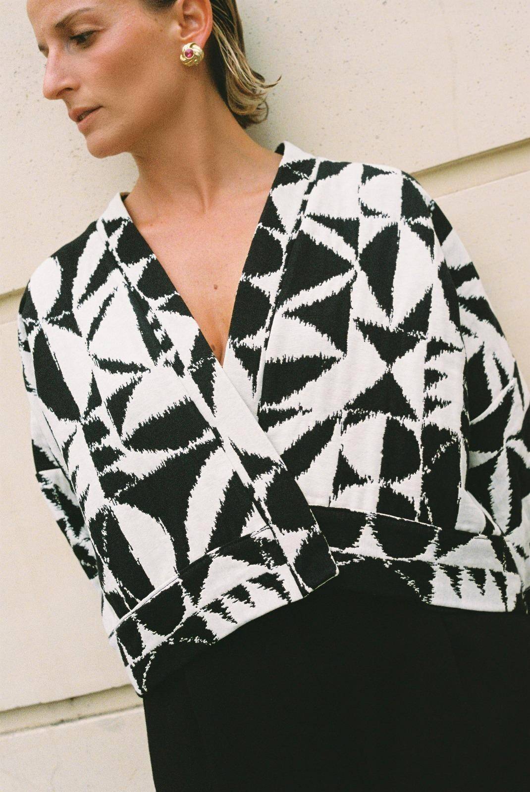 Atelier Sarita – Kimono Kuma en jacquard noir et blanc. Version courte et structurée du kimono, confectionnée à la main à Paris en série limitée. Réalisée dans un jacquard épais mais souple provenant d’une maison de textile française reconnue depuis plus de 200 ans pour son exigence en matière de traçabilité, de production locale et de durabilité. Une pièce audacieuse et graphique, parfaite pour habiller l’automne avec allure.