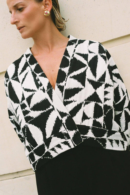 Atelier Sarita – Kimono Kuma en jacquard noir et blanc. Version courte et structurée du kimono, confectionnée à la main à Paris en série limitée. Réalisée dans un jacquard épais mais souple provenant d’une maison de textile française reconnue depuis plus de 200 ans pour son exigence en matière de traçabilité, de production locale et de durabilité. Une pièce audacieuse et graphique, parfaite pour habiller l’automne avec allure.