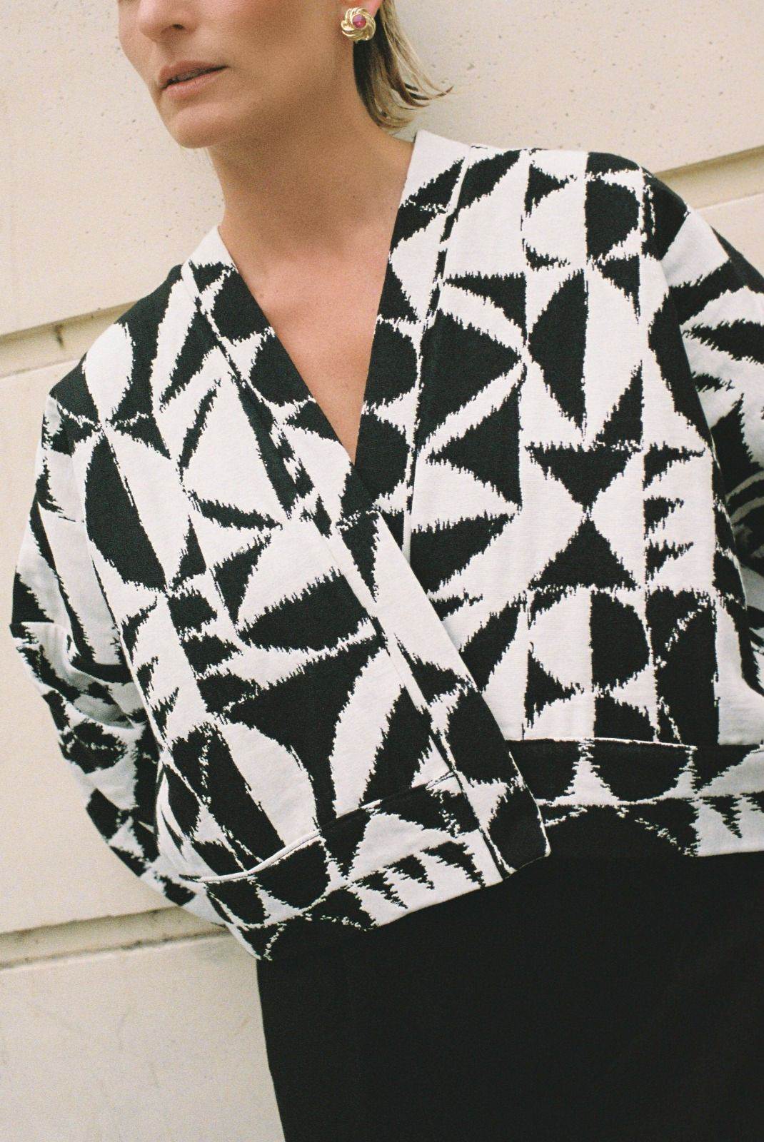 Atelier Sarita – Kimono Kuma en jacquard noir et blanc. Version courte et structurée du kimono, confectionnée à la main à Paris en série limitée. Réalisée dans un jacquard épais mais souple provenant d’une maison de textile française reconnue depuis plus de 200 ans pour son exigence en matière de traçabilité, de production locale et de durabilité. Une pièce audacieuse et graphique, parfaite pour habiller l’automne avec allure.