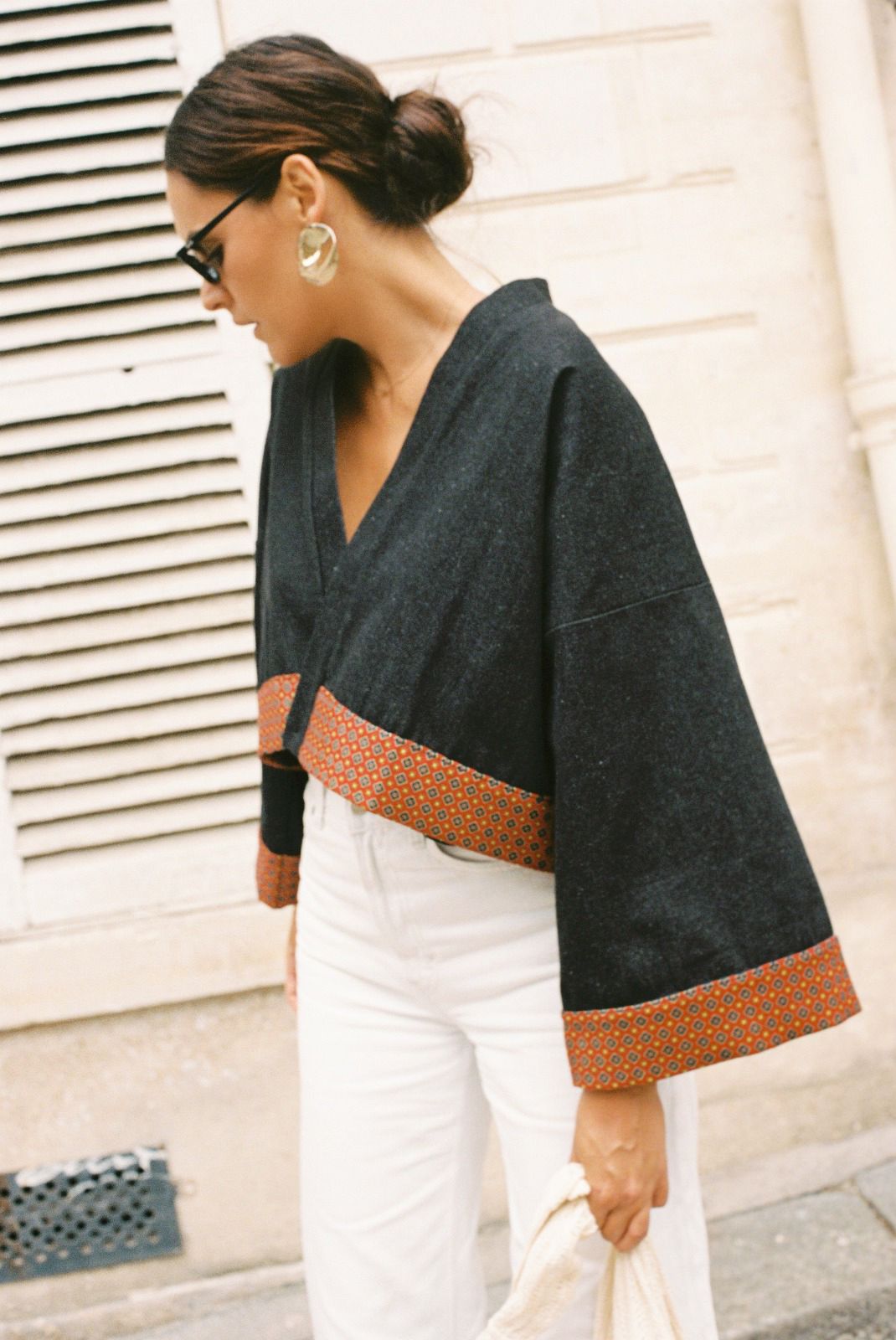 Atelier Sarita – Kimono Perret en denim noir avec parements en soie et laine rouge à motifs géométriques. Veste kimono courte et structurée, confectionnée à la main à Paris à partir de matières naturelles et upcyclées. Une pièce urbaine inspirée de l’architecture parisienne et pensée pour un vestiaire élégant et responsable.