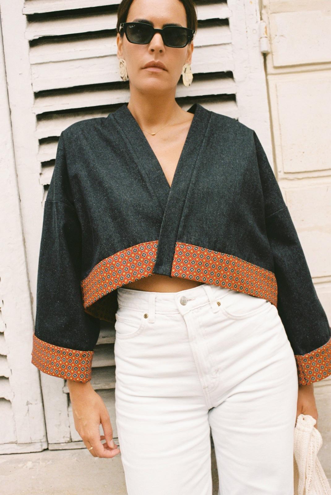 Atelier Sarita – Kimono Perret en denim noir avec parements en soie et laine rouge à motifs géométriques. Veste kimono courte et structurée, confectionnée à la main à Paris à partir de matières naturelles et upcyclées. Une pièce urbaine inspirée de l’architecture parisienne et pensée pour un vestiaire élégant et responsable.