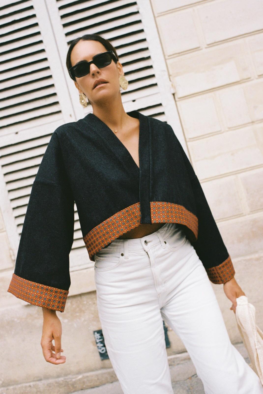 Atelier Sarita – Kimono Perret en denim noir avec parements en soie et laine rouge à motifs géométriques. Veste kimono courte et structurée, confectionnée à la main à Paris à partir de matières naturelles et upcyclées. Une pièce urbaine inspirée de l’architecture parisienne et pensée pour un vestiaire élégant et responsable.