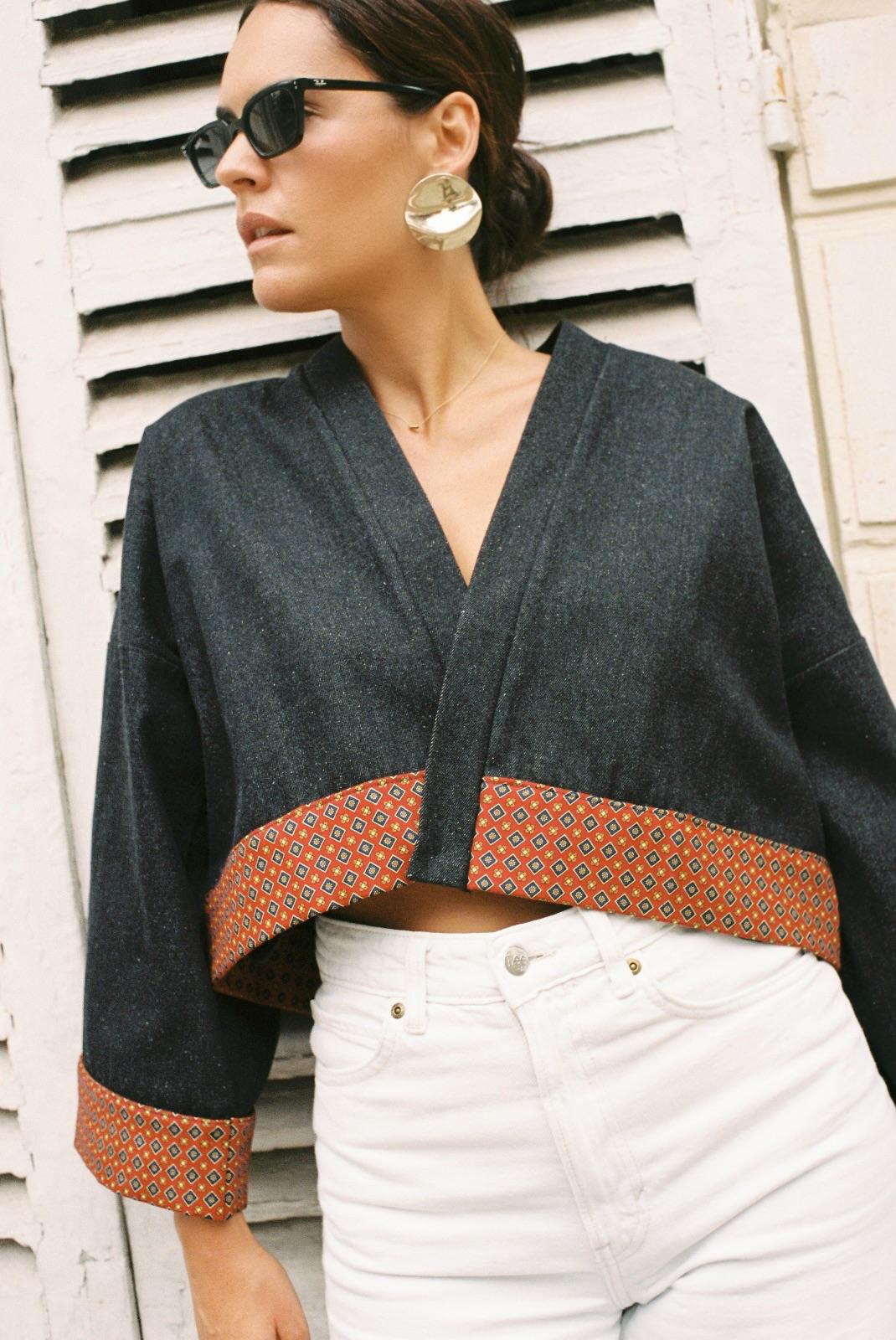 Atelier Sarita – Kimono Perret en denim noir avec parements en soie et laine rouge à motifs géométriques. Veste kimono courte et structurée, confectionnée à la main à Paris à partir de matières naturelles et upcyclées. Une pièce urbaine inspirée de l’architecture parisienne et pensée pour un vestiaire élégant et responsable.