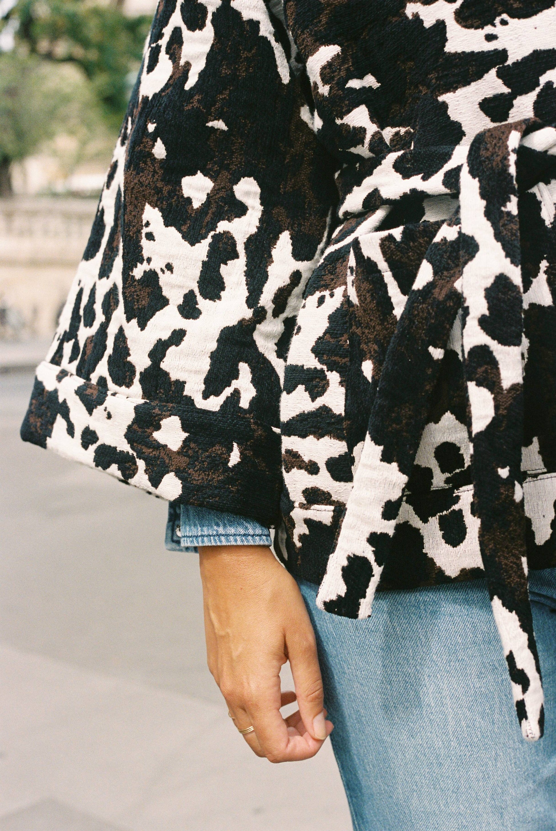 Atelier Sarita – Kimono Renzo en jacquard motif vache. Une coupe ample et affirmée qui revisite le kimono en version urbaine et audacieuse. Confectionné à la main à Paris en série limitée, ce modèle est réalisé dans un jacquard épais et texturé, issu d’une maison textile française de renom, garante d’un savoir-faire séculaire et d’une production durable. Avec son imprimé graphique noir et blanc façon animalier, Renzo est une pièce forte du vestiaire contemporain.