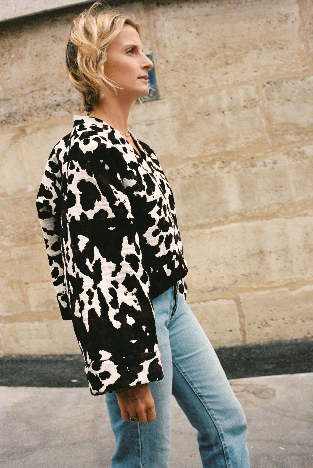 Atelier Sarita – Kimono Roger en jacquard motif vache. Une coupe courte et audacieuse, pensée comme une pièce arty et urbaine, qui bouscule les codes du vestiaire parisien. Confectionné à la main à Paris en série limitée, ce kimono est réalisé dans un jacquard épais et texturé, issu d’une maison textile française reconnue pour son savoir-faire et son exigence en matière de durabilité. Une pièce singulière qui célèbre l’originalité et le mouvement urbain.