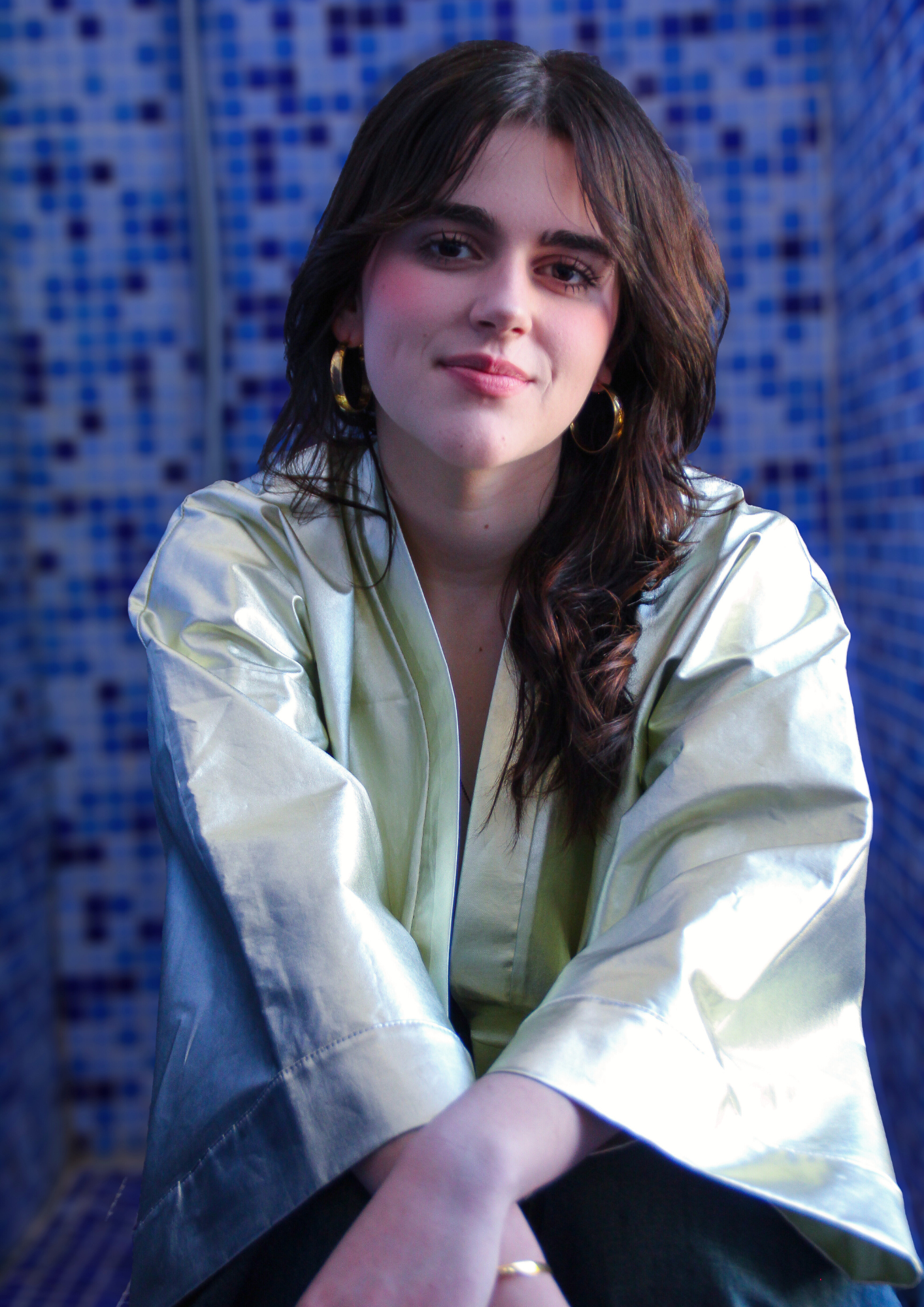 Femme portant un kimono court en coton doré métallisé, photographiée dans une salle de bain aux carreaux bleus.