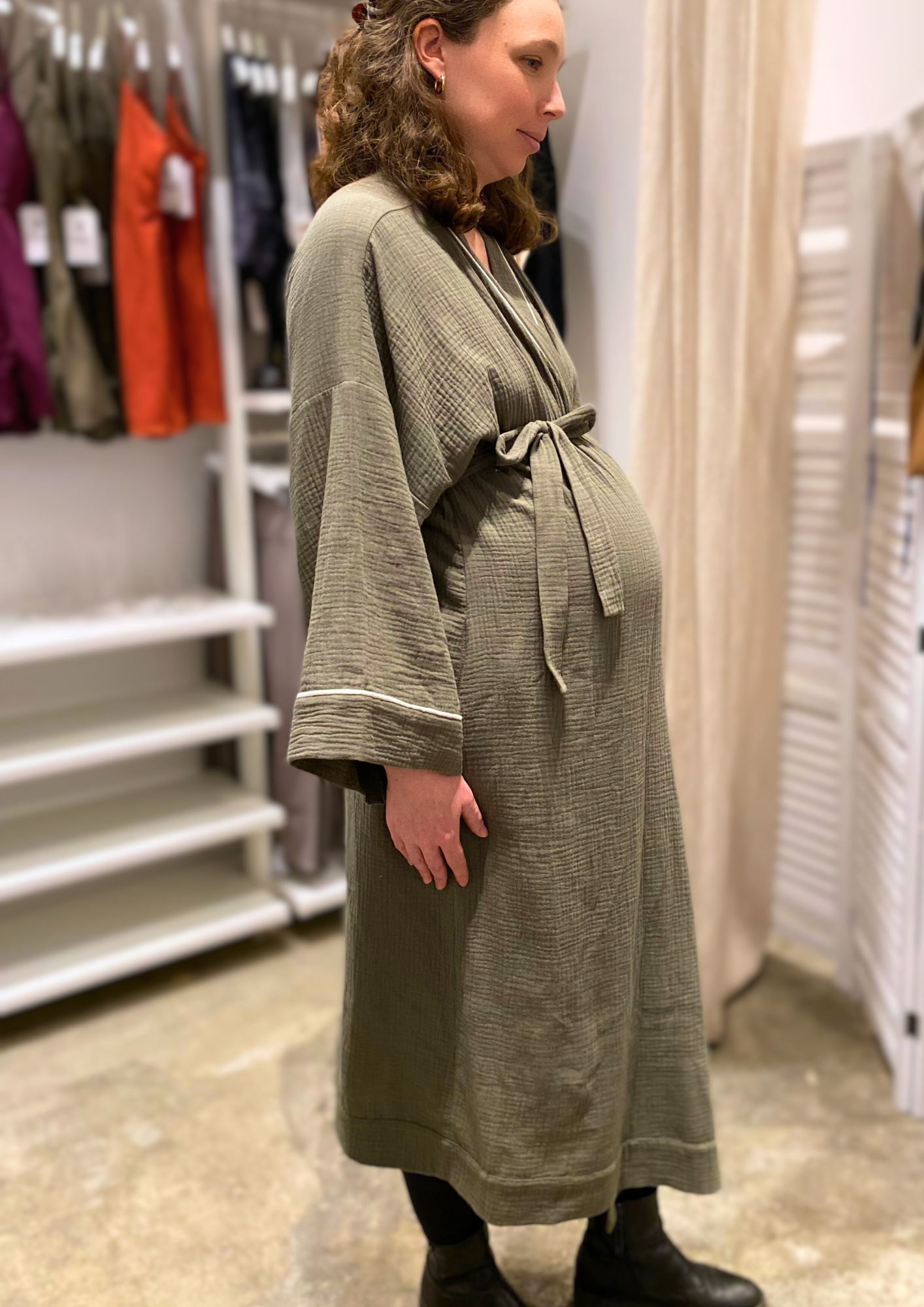 Jeune femme enceinte vêtue d'un Kimono de maternité en gaze de coton kaki avec liseré blanc, coupe ample et enveloppante pour un confort optimal.