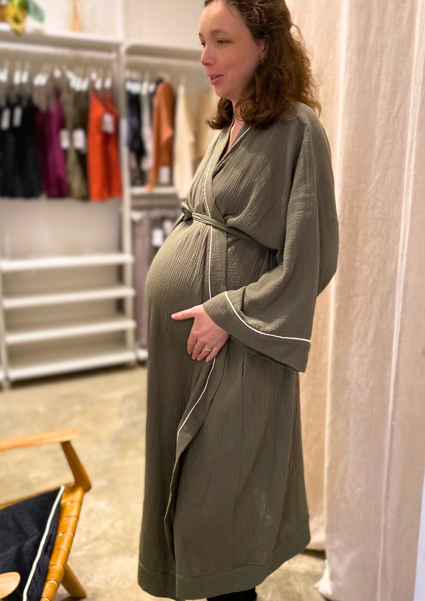 Jeune femme enceinte vêtue d'un Kimono de maternité en gaze de coton kaki avec liseré blanc, coupe ample et enveloppante pour un confort optimal.