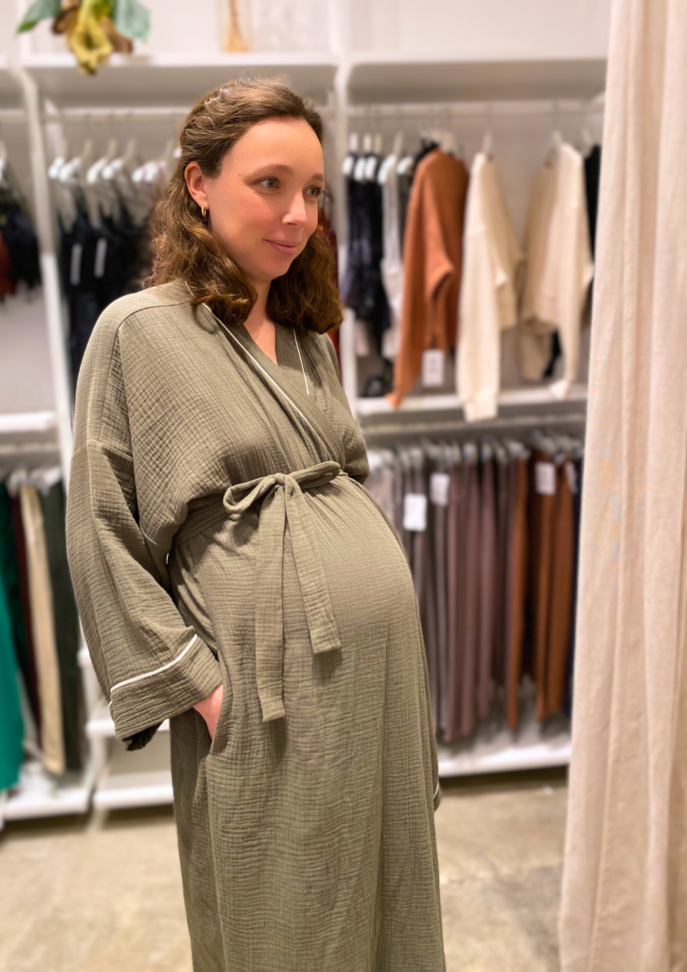 Jeune femme enceinte vêtue d'un Kimono de maternité en gaze de coton kaki avec liseré blanc, coupe ample et enveloppante pour un confort optimal.