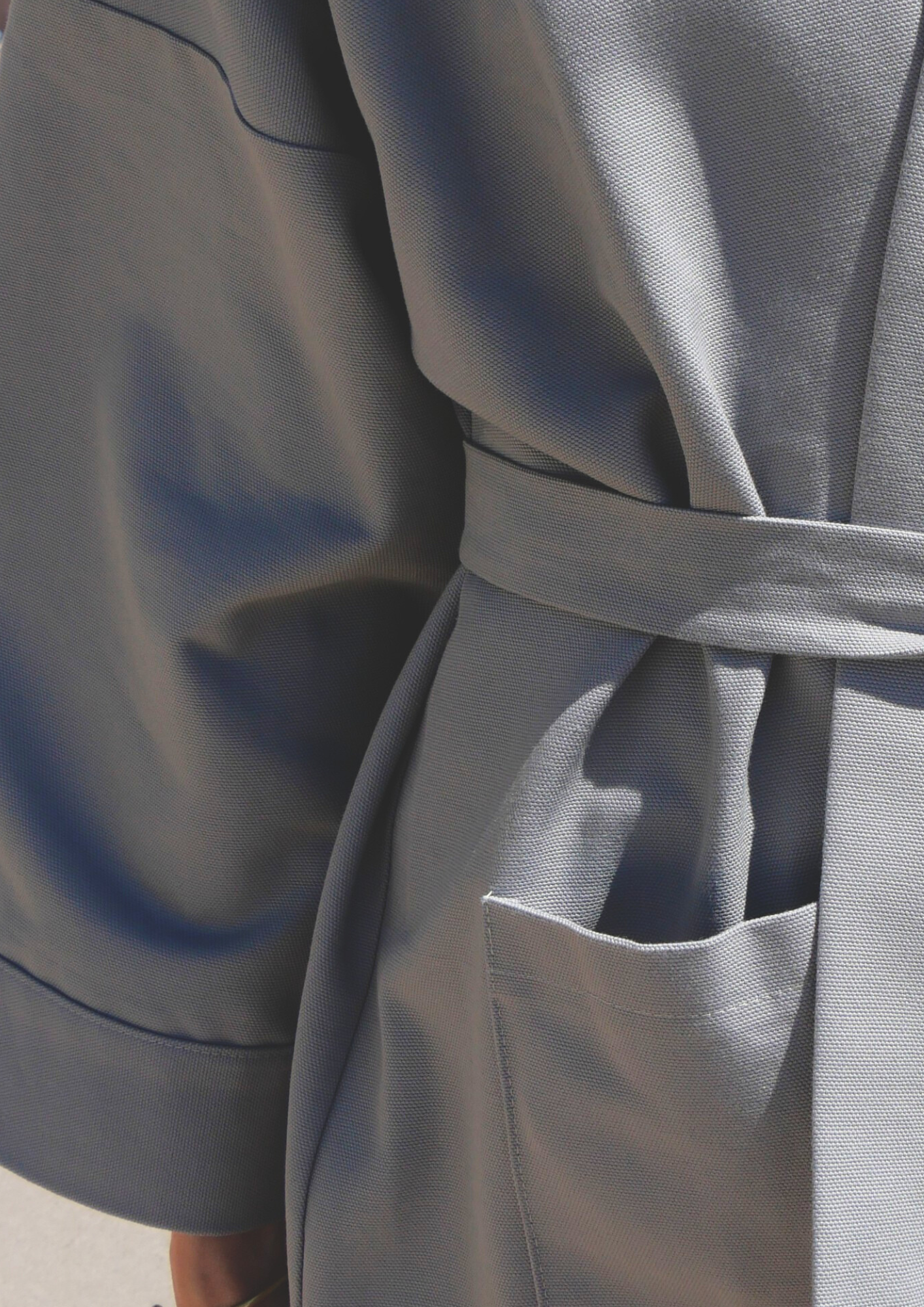 Femme portant un kimono gris en coton biologique, coupe ample avec ceinture. Pièce confectionnée à la main à Paris, par Atelier Sarita.