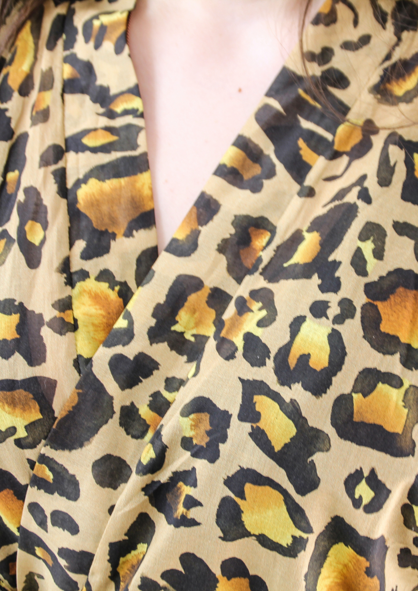 Femme portant un kimono long en voile de coton motif léopard, noué à la taille, dans une pièce lumineuse.