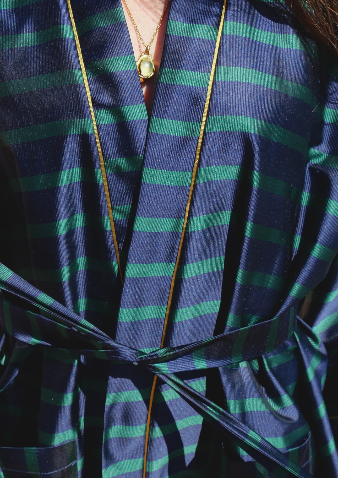 Femme portant un kimono mi-long en soie bleu et vert rehaussé d’un liseré doré, modèle Atelier Sarita fait main à Paris.