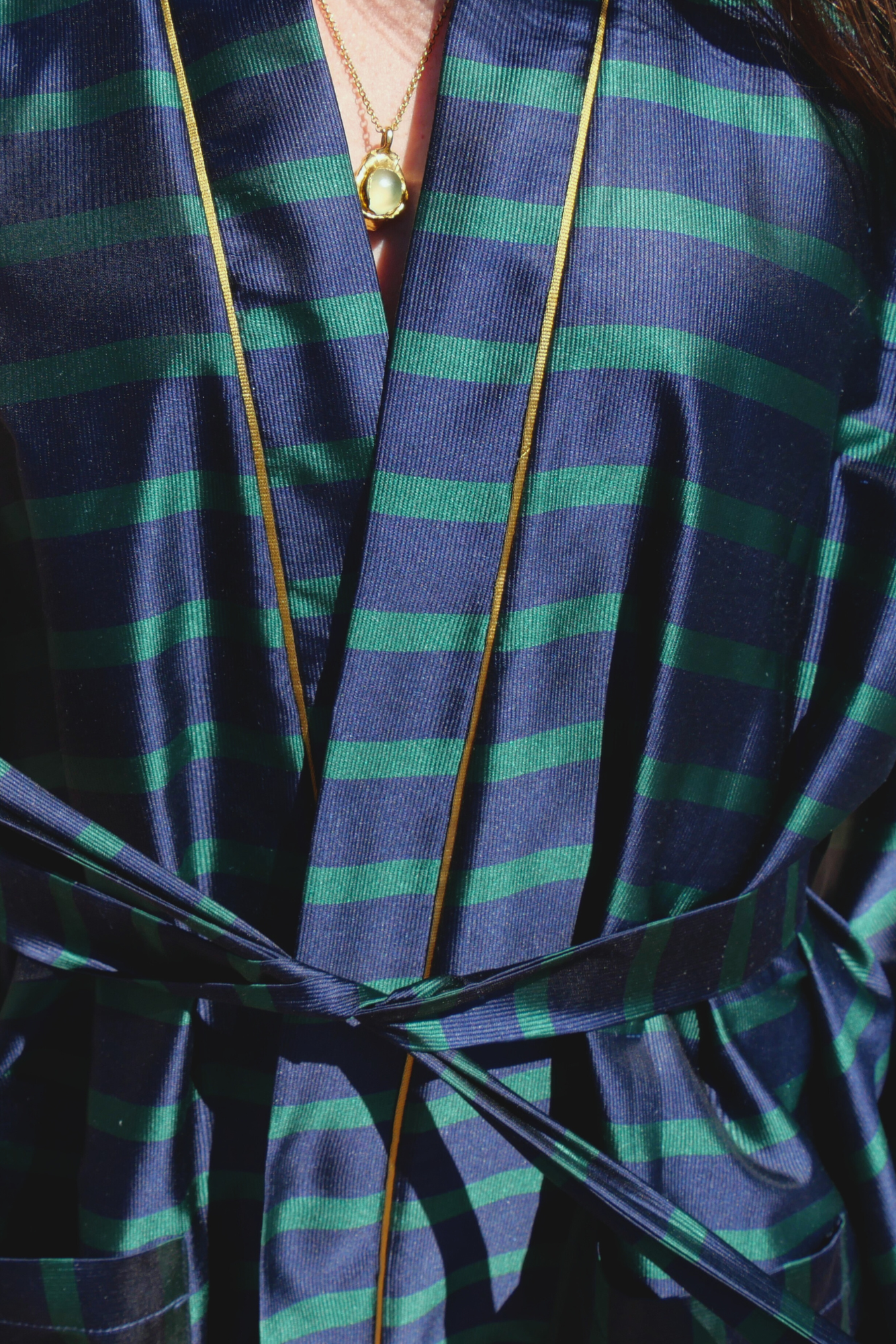 Femme portant un kimono mi-long en soie bleu et vert rehaussé d’un liseré doré, modèle Atelier Sarita fait main à Paris.