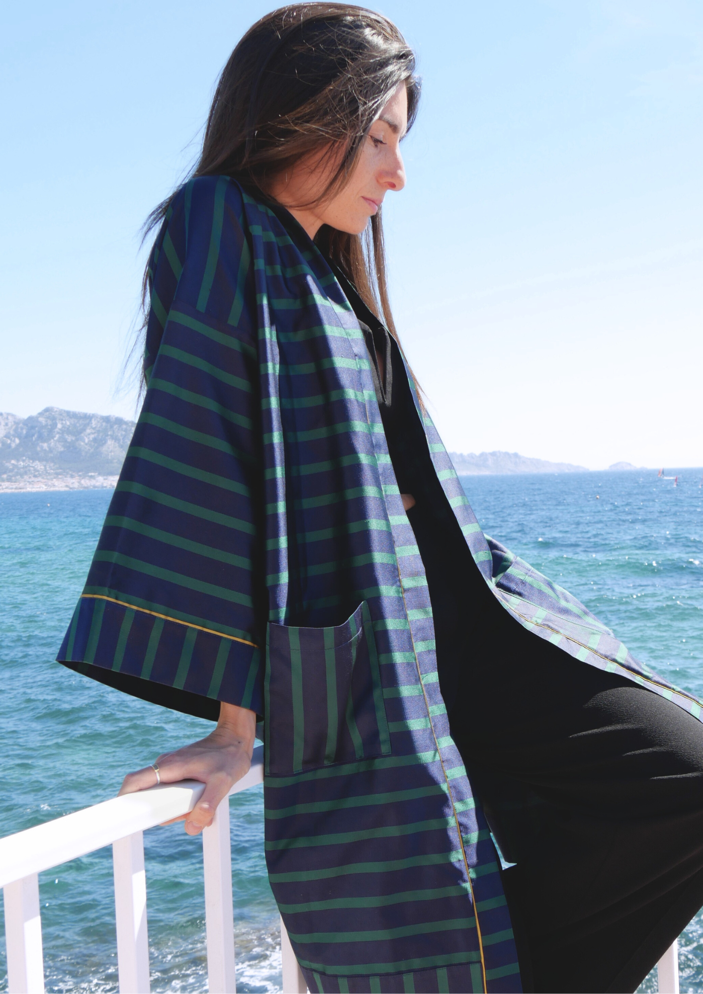 Femme portant un kimono mi-long en soie bleu et vert rehaussé d’un liseré doré, modèle Atelier Sarita fait main à Paris.