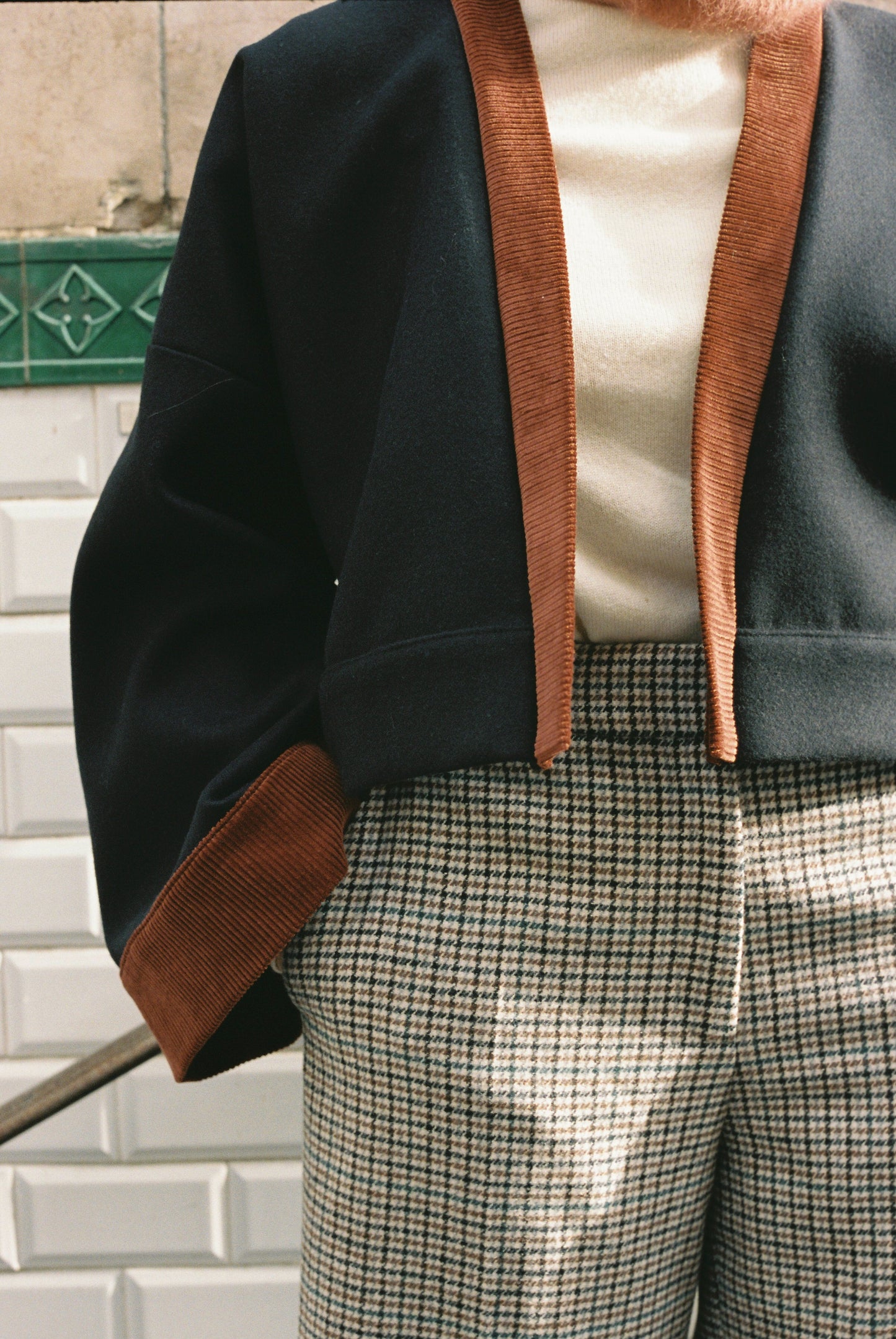 Femme portant le kimono VÉRO Atelier Sarita, un kimono court en laine noire caviar avec finitions en velours coton couleur oud, photographié dans une entrée de métro parisien. Modèle au style architectural et urbain, confectionné à la main à Paris.