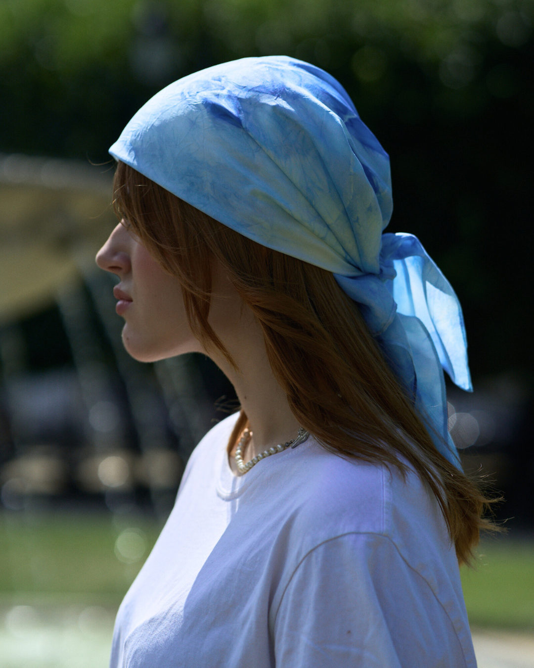 Jeune femme portant un carré en soie 70x70 cm noué en soie pongé teint à la main à Paris selon la technique Shibori – motif Scrunch