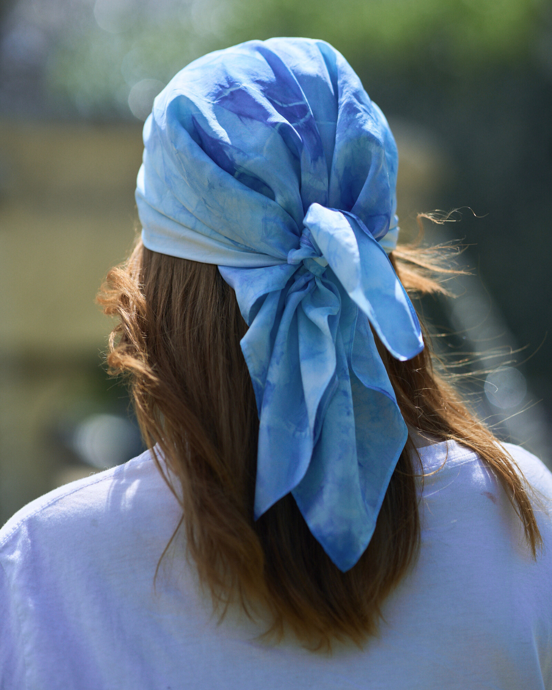 Jeune femme portant un carré en soie 70x70 cm noué en soie pongé teint à la main à Paris selon la technique Shibori – motif Scrunch