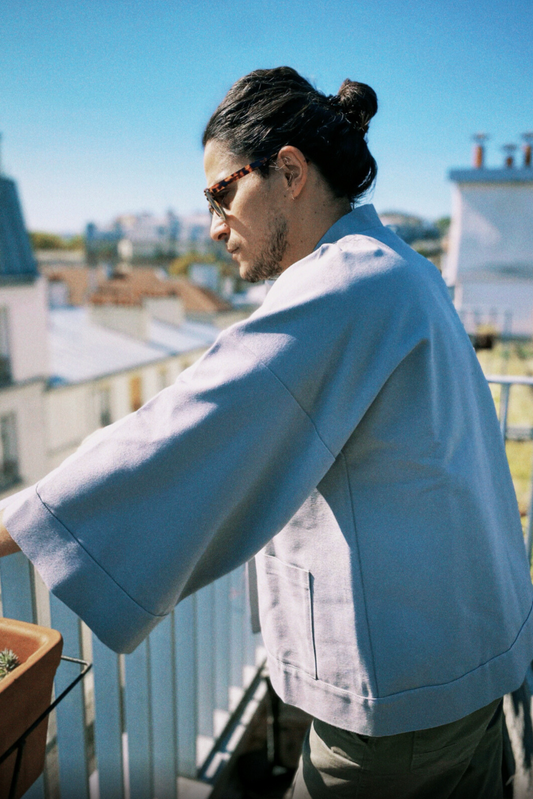 Homme portant un kimono gris en coton biologique, coupe ample avec ceinture. Pièce confectionnée à la main à Paris, par Atelier Sarita.