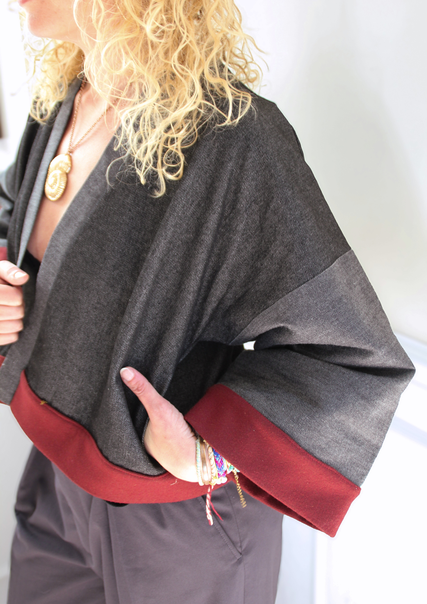 Cardigan kimono en denim noir et gris avec finitions en laine bordeaux et poches, coupe ample et style épuré.