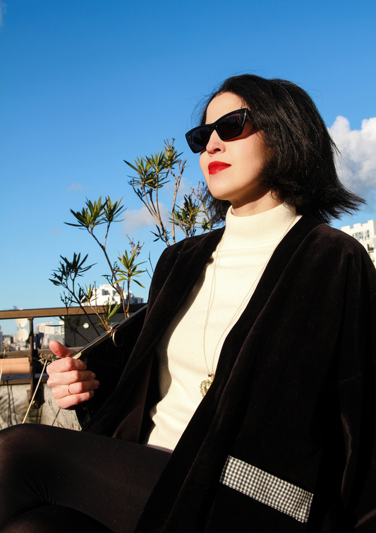 Femme portant élégamment un kimono court en velours côtelé noir et empiècement en laine vichy. L'élégance assumée, le chic décomplexé.