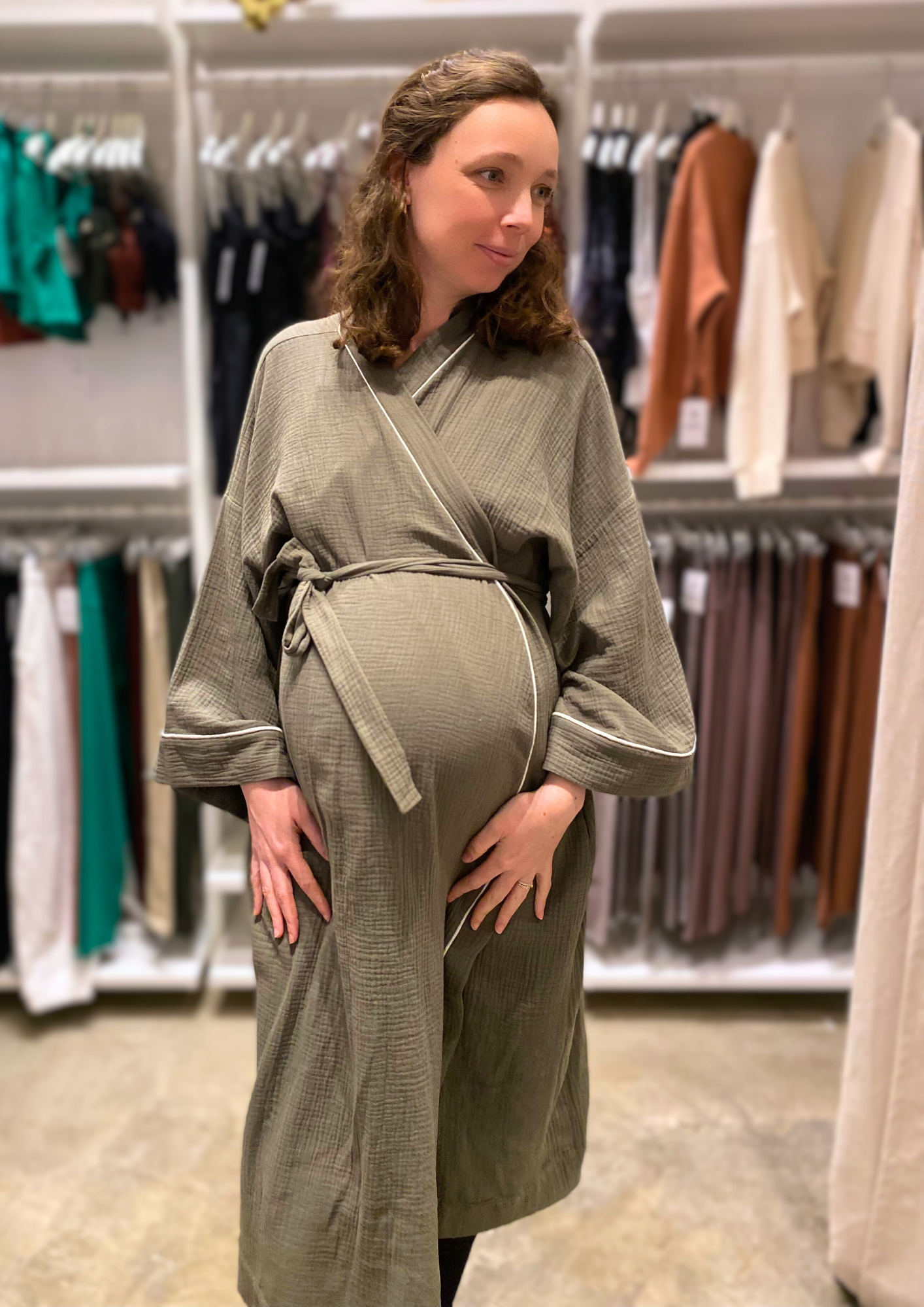 Jeune femme enceinte vêtue d'un Kimono de maternité en gaze de coton kaki avec liseré blanc, coupe ample et enveloppante pour un confort optimal.