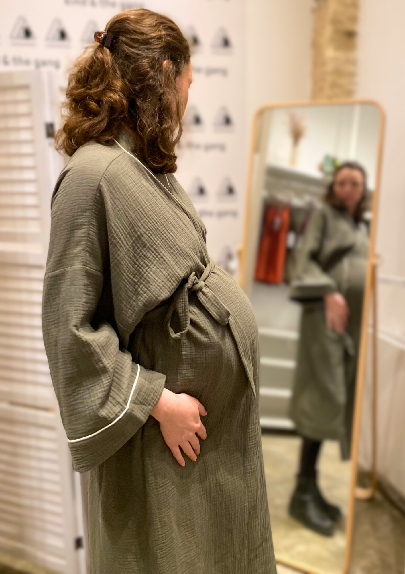 Jeune femme enceinte vêtue d'un Kimono de maternité en gaze de coton kaki avec liseré blanc, coupe ample et enveloppante pour un confort optimal.