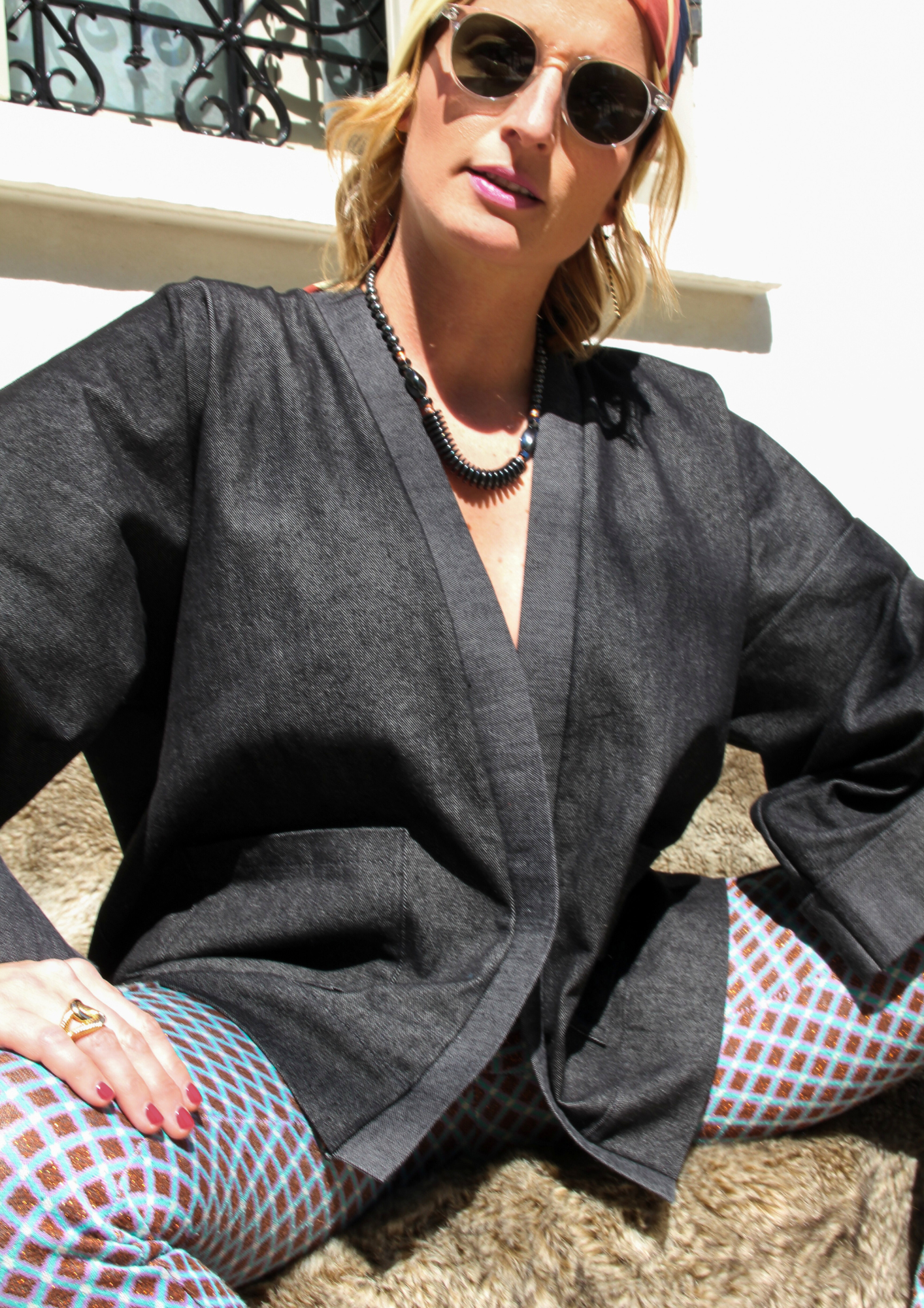 Femme portant un kimono court en denim noir 100% coton, avec manches larges et poches plaquées, fait à la main à Paris.