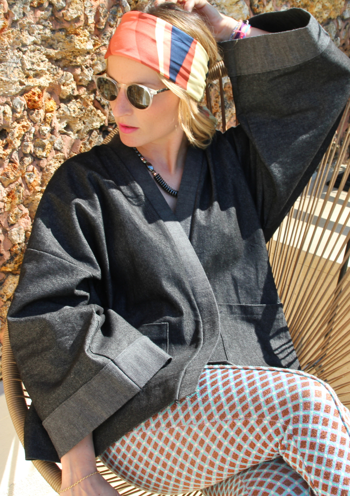 Femme portant un kimono court en denim noir 100% coton, avec manches larges et poches plaquées, fait à la main à Paris.