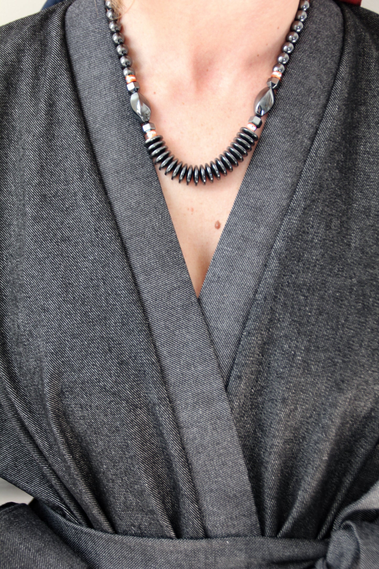 Femme portant un kimono court en denim noir 100% coton, avec manches larges et poches plaquées, fait à la main à Paris.