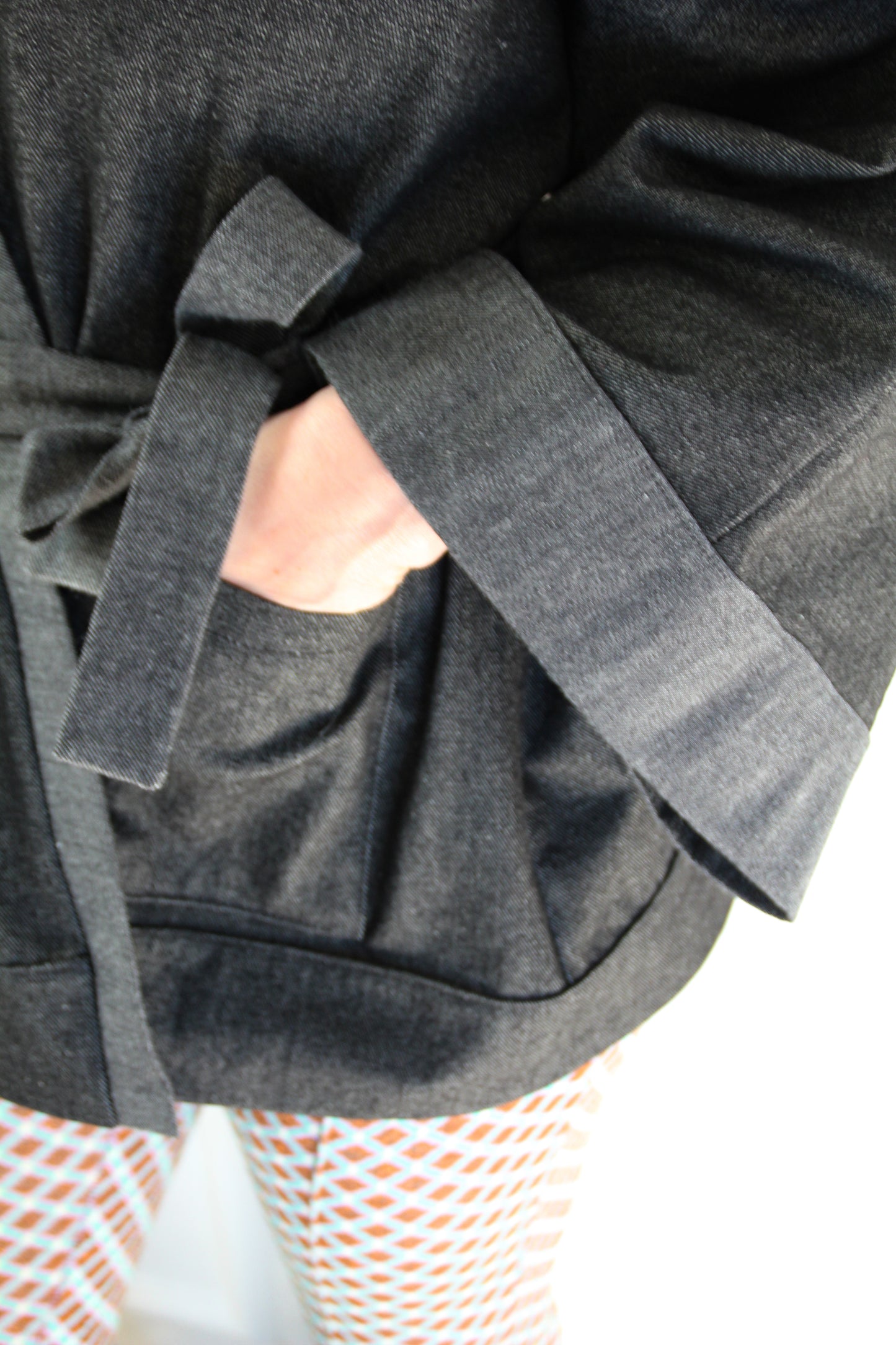 Femme portant un kimono court en denim noir 100% coton, avec manches larges et poches plaquées, fait à la main à Paris.