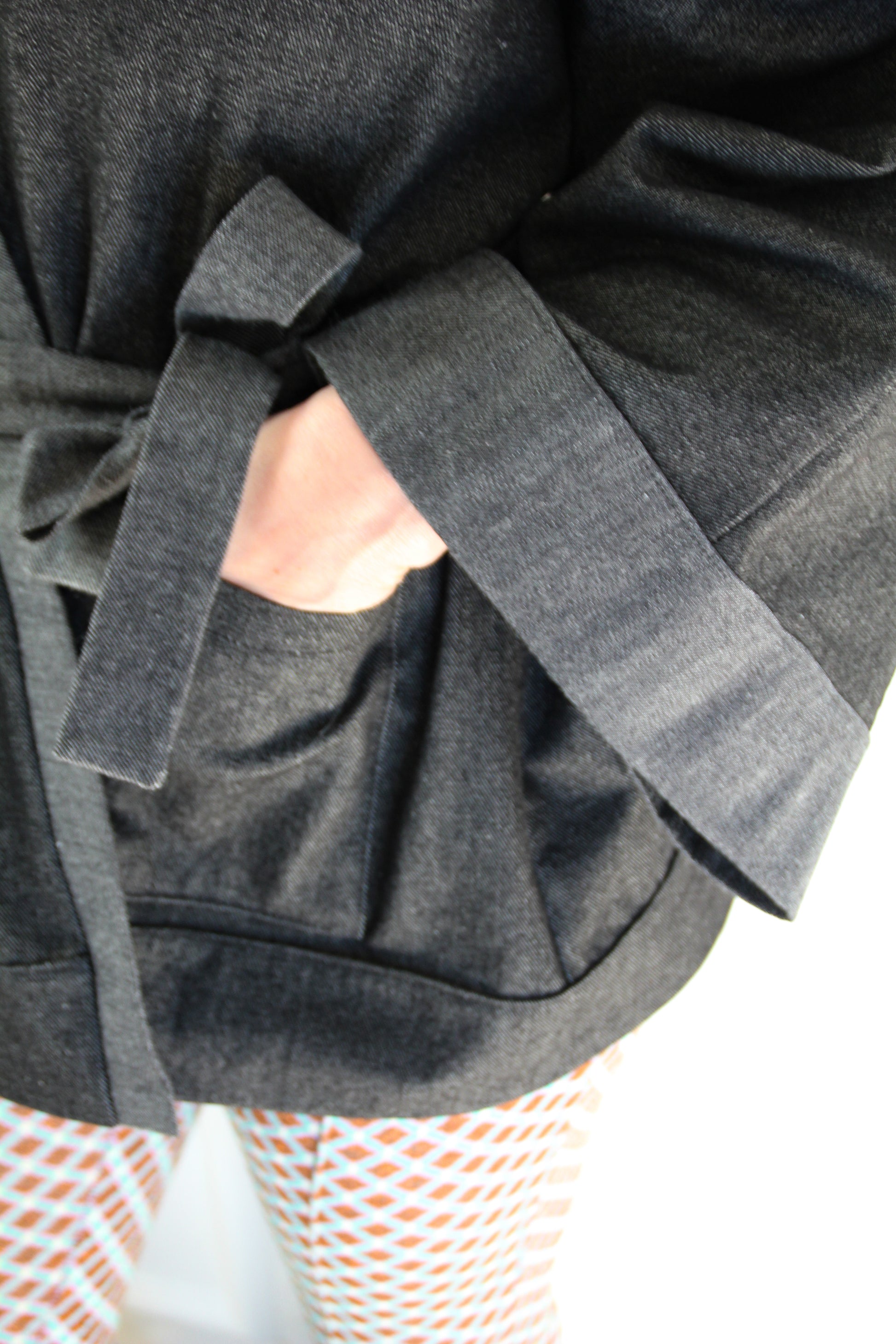 Femme portant un kimono court en denim noir 100% coton, avec manches larges et poches plaquées, fait à la main à Paris.