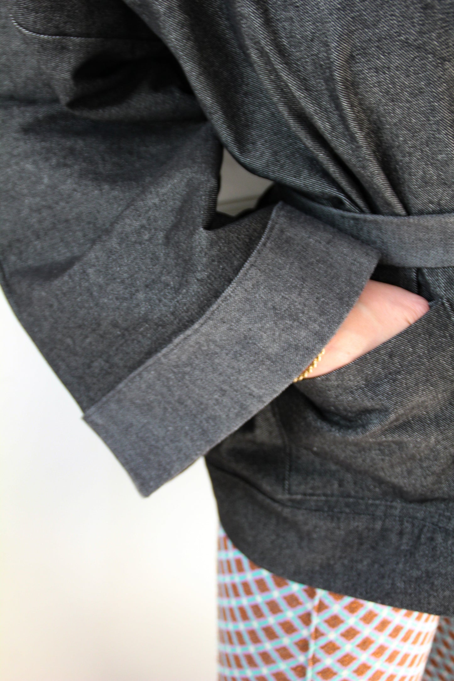 Femme portant un kimono court en denim noir 100% coton, avec manches larges et poches plaquées, fait à la main à Paris.