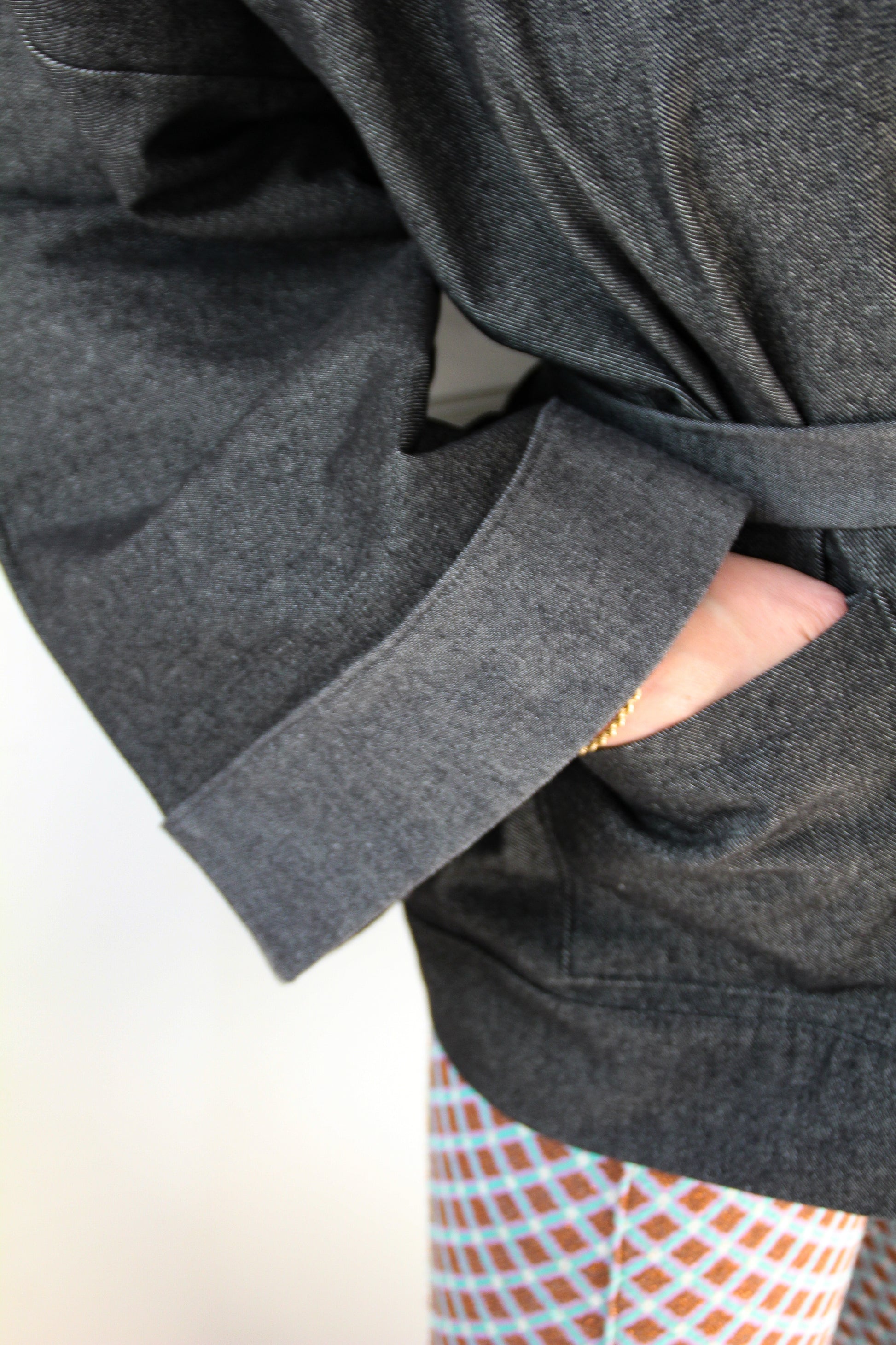 Femme portant un kimono court en denim noir 100% coton, avec manches larges et poches plaquées, fait à la main à Paris.