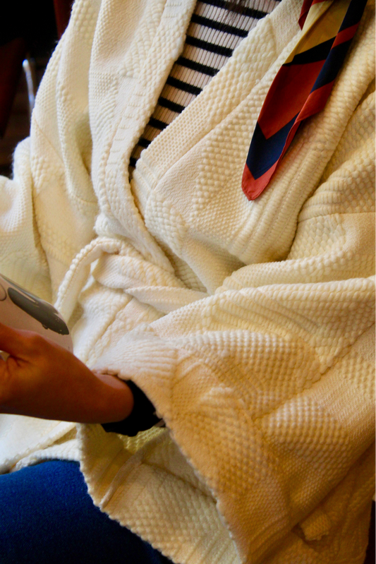 Jeune femme au look retro porte un kimono en laine blanc cassé, doux et élégant, idéal pour les douces journées printanières. Cette pièce unique est confectionnée à la main avec soin à Paris.