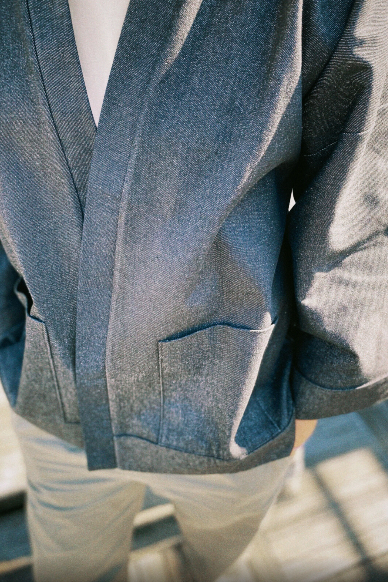 Homme portant un kimono court en denim noir 100% coton, avec manches larges et poches plaquées, fait à la main à Paris.