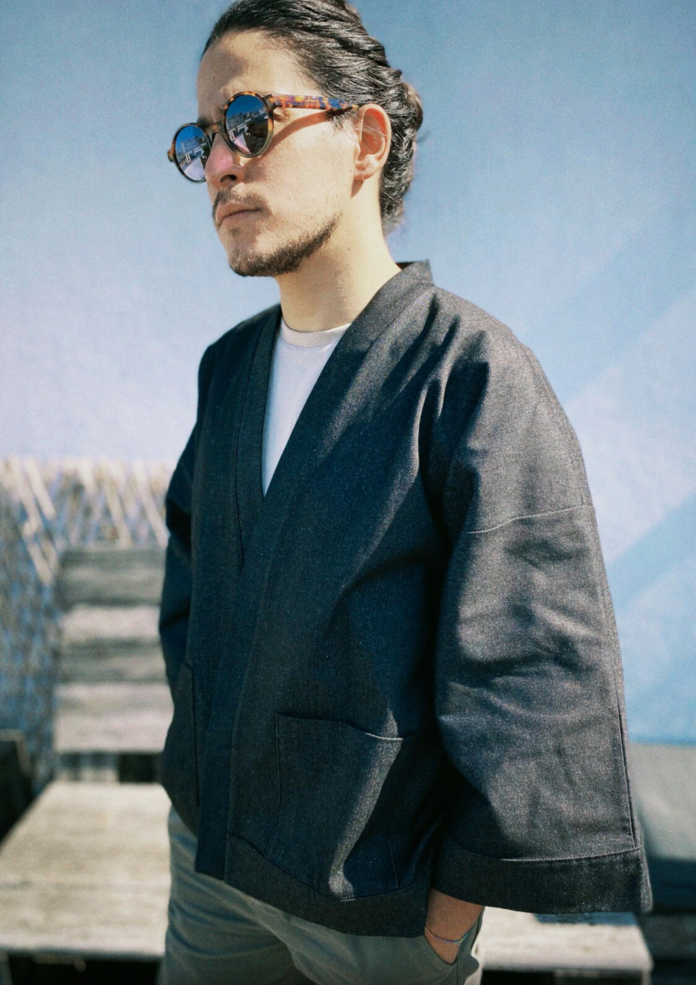Homme portant un kimono court en denim noir 100% coton, avec manches larges et poches plaquées, fait à la main à Paris.