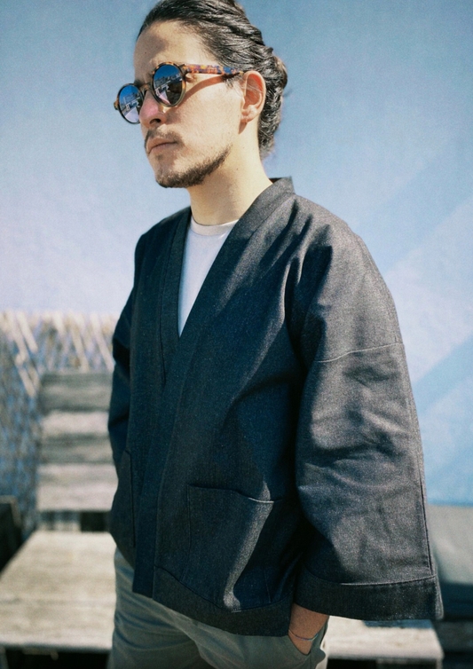 Homme portant un kimono court en denim noir 100% coton, avec manches larges et poches plaquées, fait à la main à Paris.
