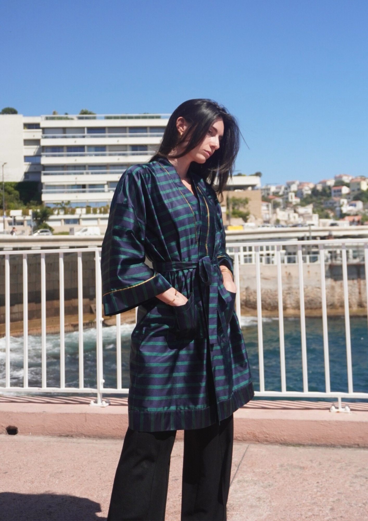 Femme portant un kimono mi-long en soie bleu et vert rehaussé d’un liseré doré, modèle Atelier Sarita fait main à Paris.