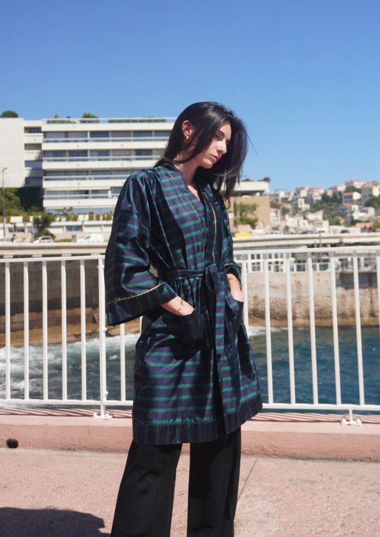 Femme portant un kimono mi-long en soie bleu et vert rehaussé d’un liseré doré, modèle Atelier Sarita fait main à Paris.
