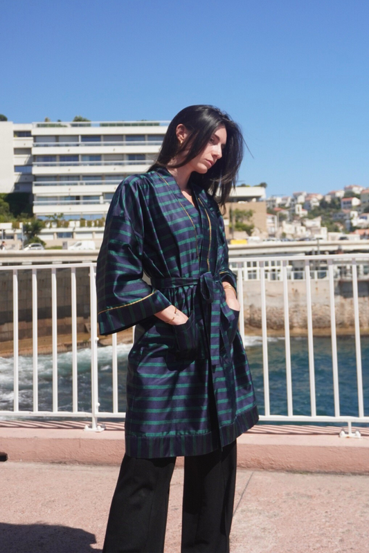 Femme portant un kimono mi-long en soie bleu et vert rehaussé d’un liseré doré, modèle Atelier Sarita fait main à Paris.