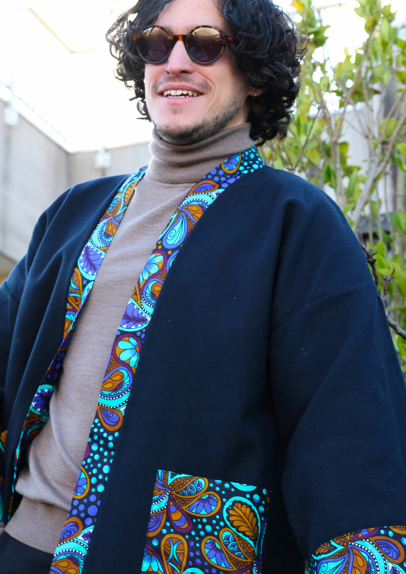 Homme portant un kimono court en coton bleu avec finitions en wax coloré, manches larges et poches assorties.