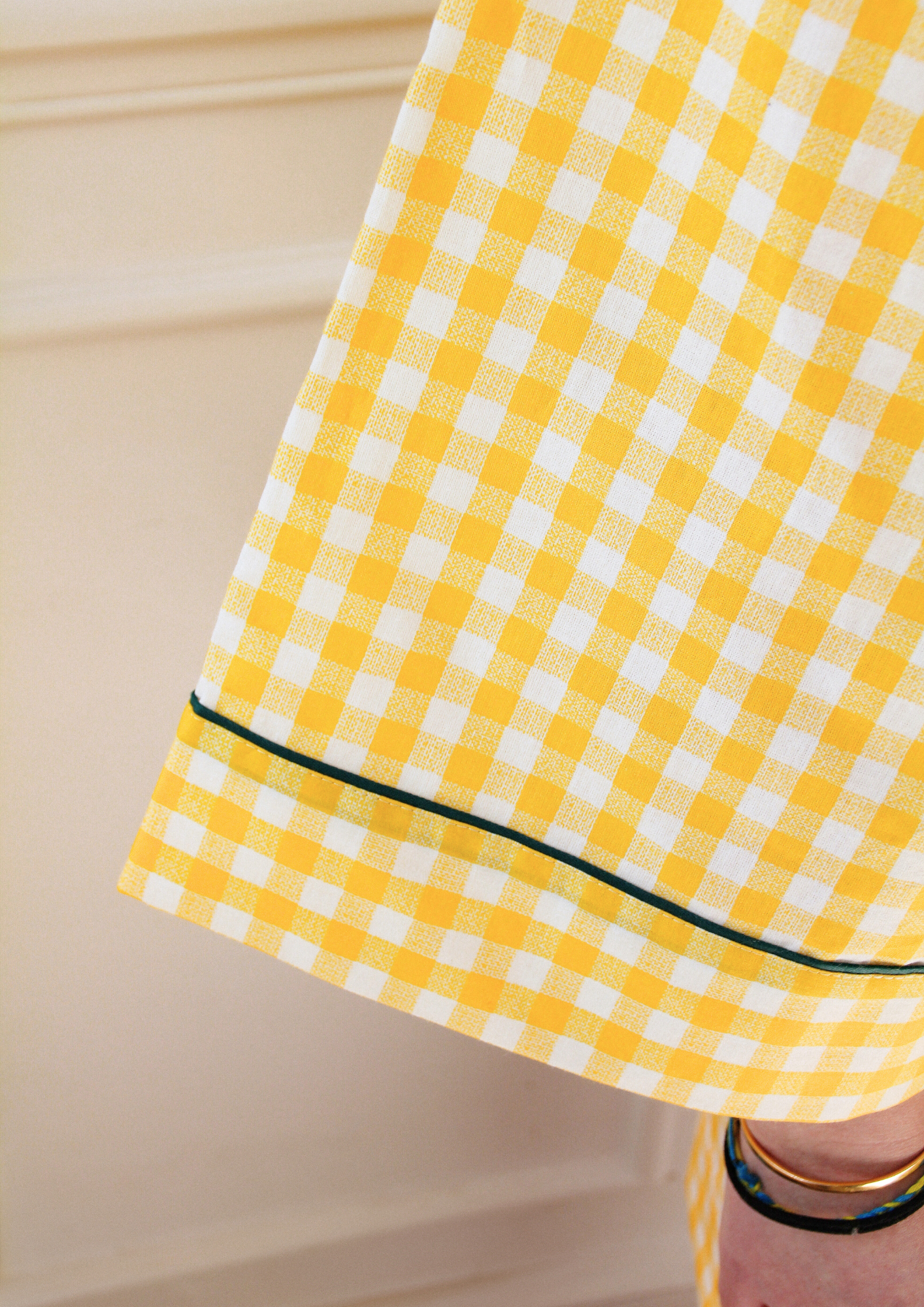 Femme portant un kimono court en coton vichy jaune à passepoil vert, noué à la taille, dans une pièce lumineuse.