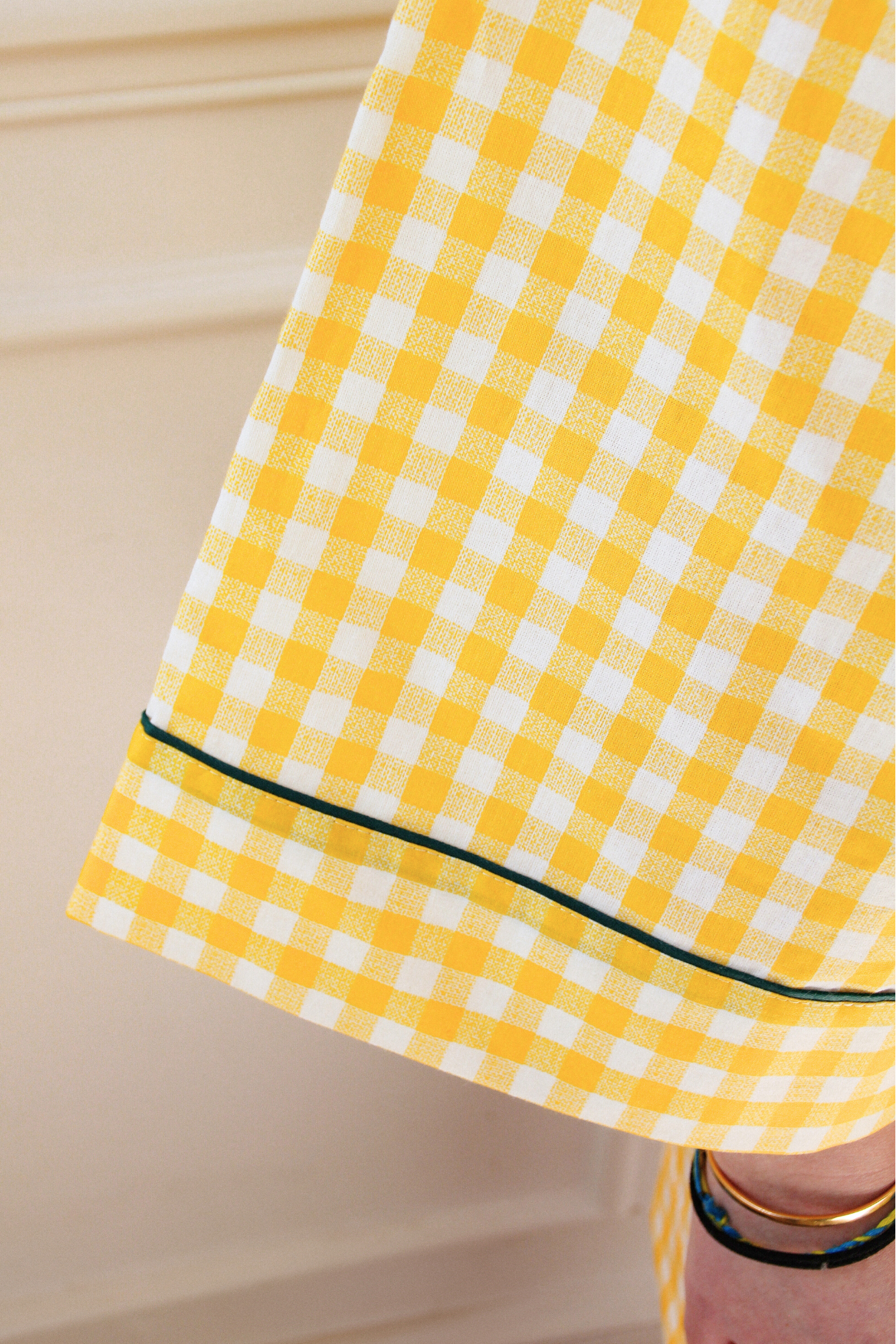 Femme portant un kimono court en coton vichy jaune à passepoil vert, noué à la taille, dans une pièce lumineuse.