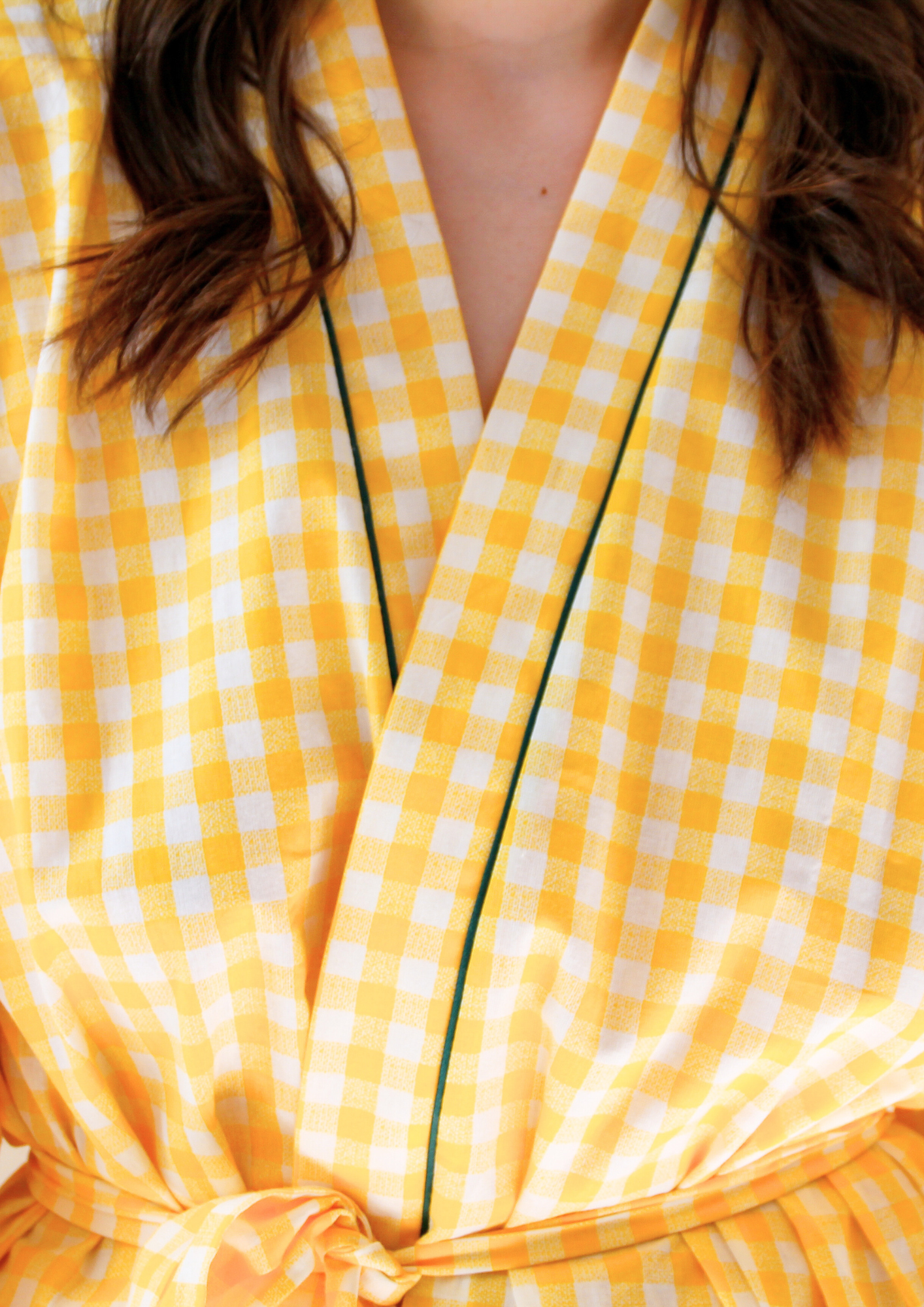 Femme portant un kimono court en coton vichy jaune à passepoil vert, noué à la taille, dans une pièce lumineuse.